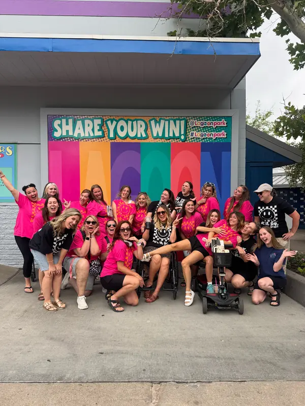 Bestie Squad members in bright pink shirts being silly together at an amusement park.